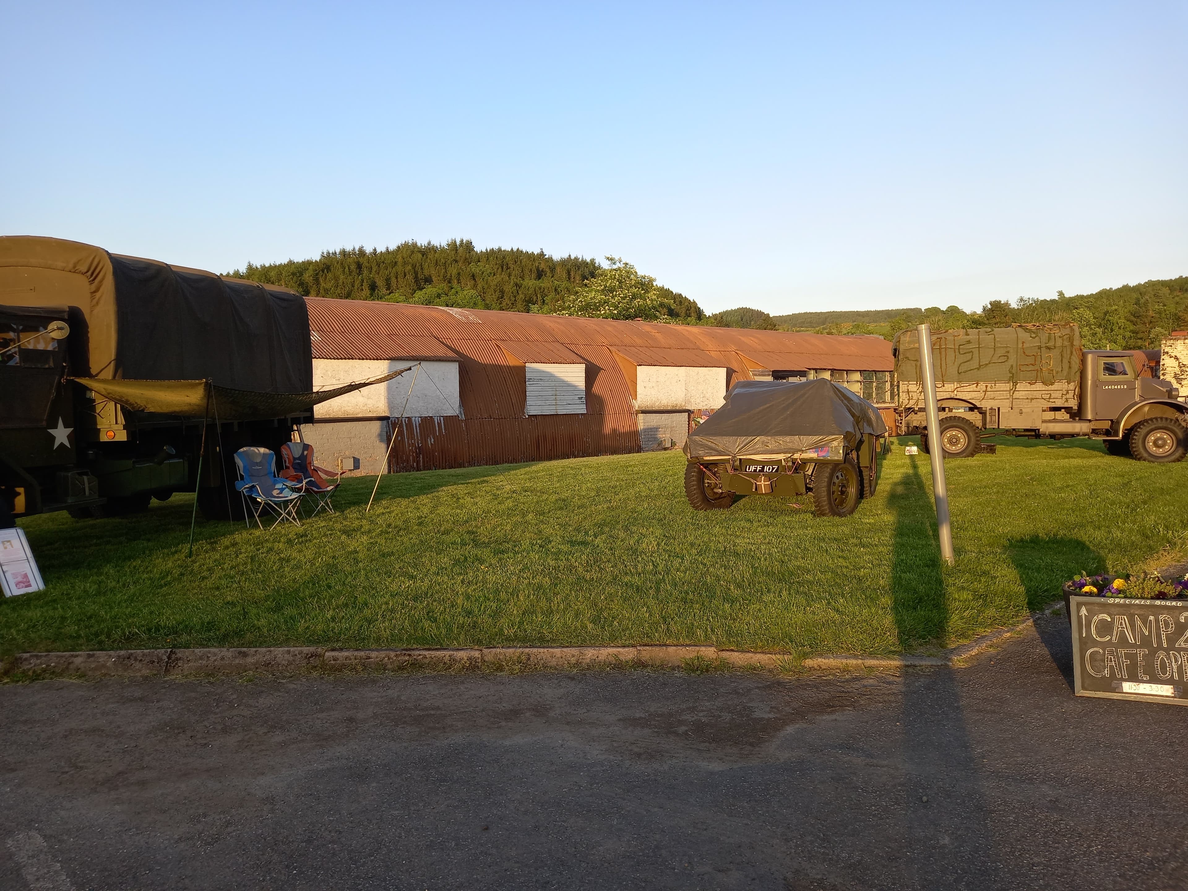 Golden-hour view of Cultybraggan Camp — a row of original corrugated iron Nissen huts with Perthshire hills beyond